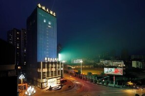 Un immeuble de grande hauteur, doté d’une enseigne lumineuse, et entouré d’un environnement urbain bien éclairé.