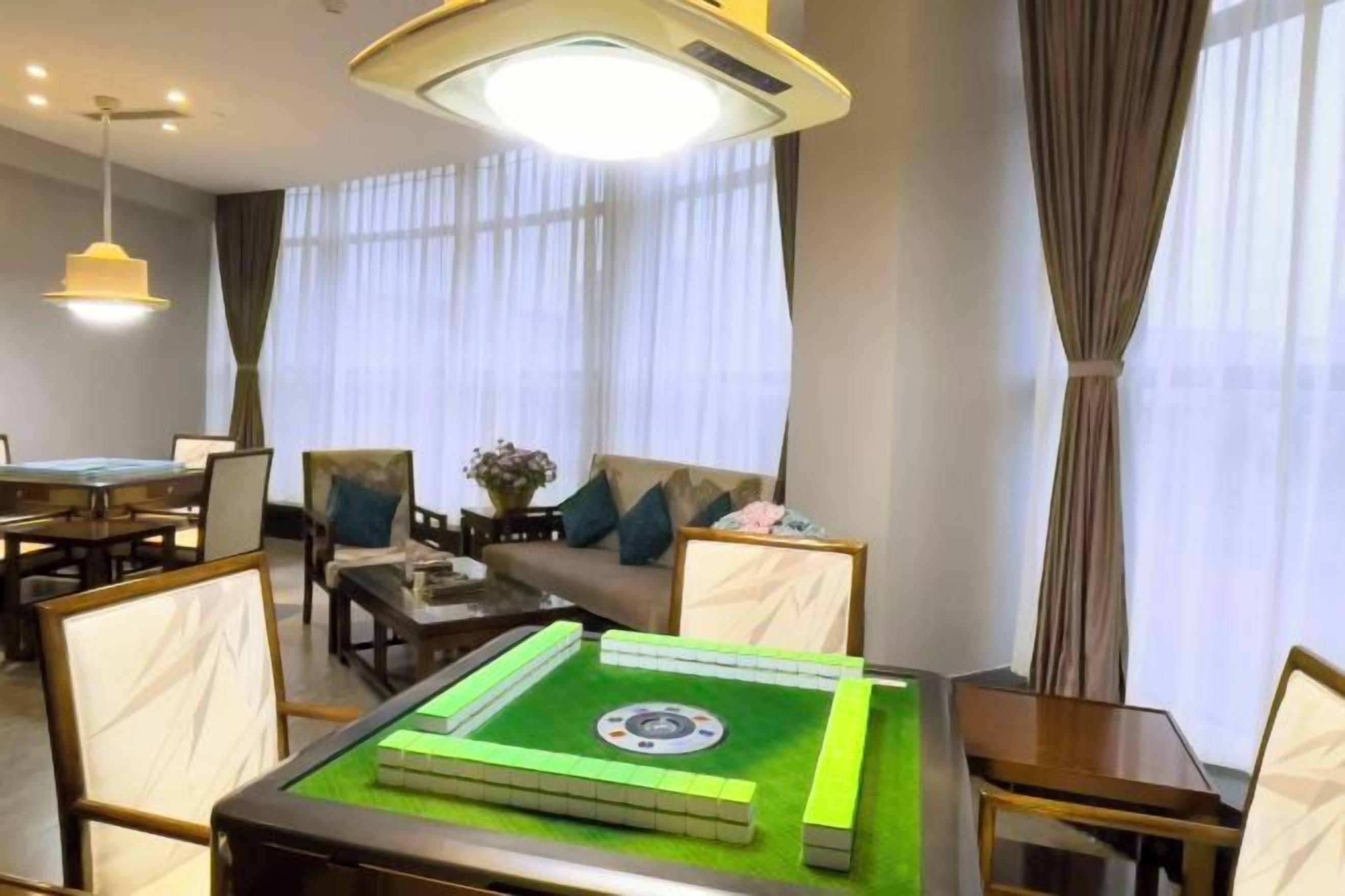 A hotel room with a pool table, a sofa, and a dining table.