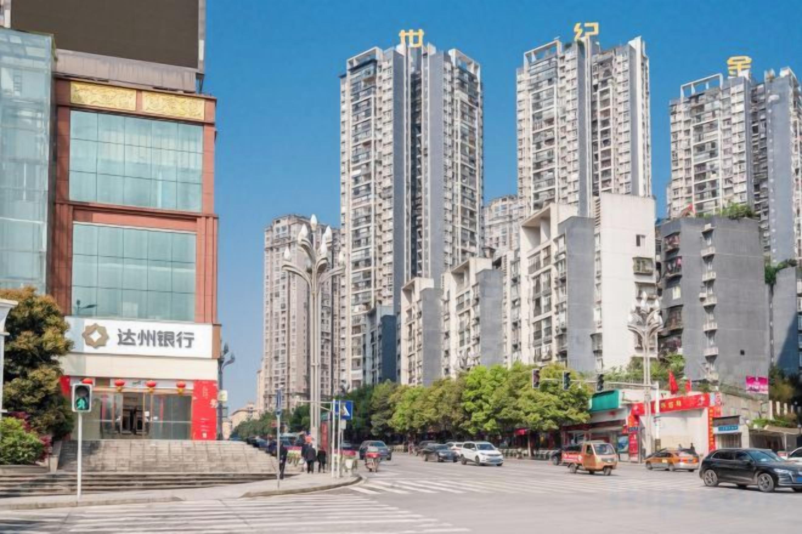 Una calle urbana con edificios altos, un banco y un paso de peatones.