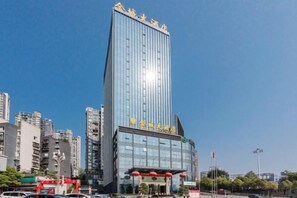 Un immeuble moderne de grande hauteur, doté d’une entrée imposante et d’une façade en verre.