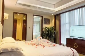 Ein Hotelzimmer mit Bett, Fernseher, Pflanze und Spiegel.