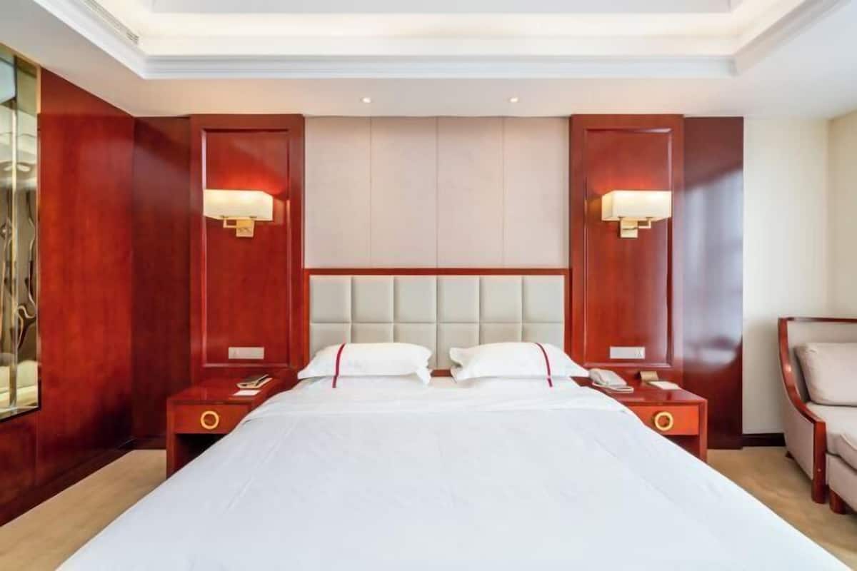 Habitación de hotel con una cama grande, dos mesitas de noche, un cabecero y lámparas fijadas a la pared.