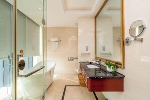 Ein modernes Badezimmer mit Duschkabine aus Glas, einer weißen Badewanne, einem Waschbecken mit Spiegel und einer kleinen Ablagefläche.