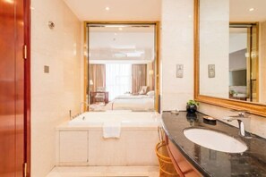 Ein modernes Badezimmer mit großem Spiegel, einer Badewanne, einem Waschbecken und einer Toilette.