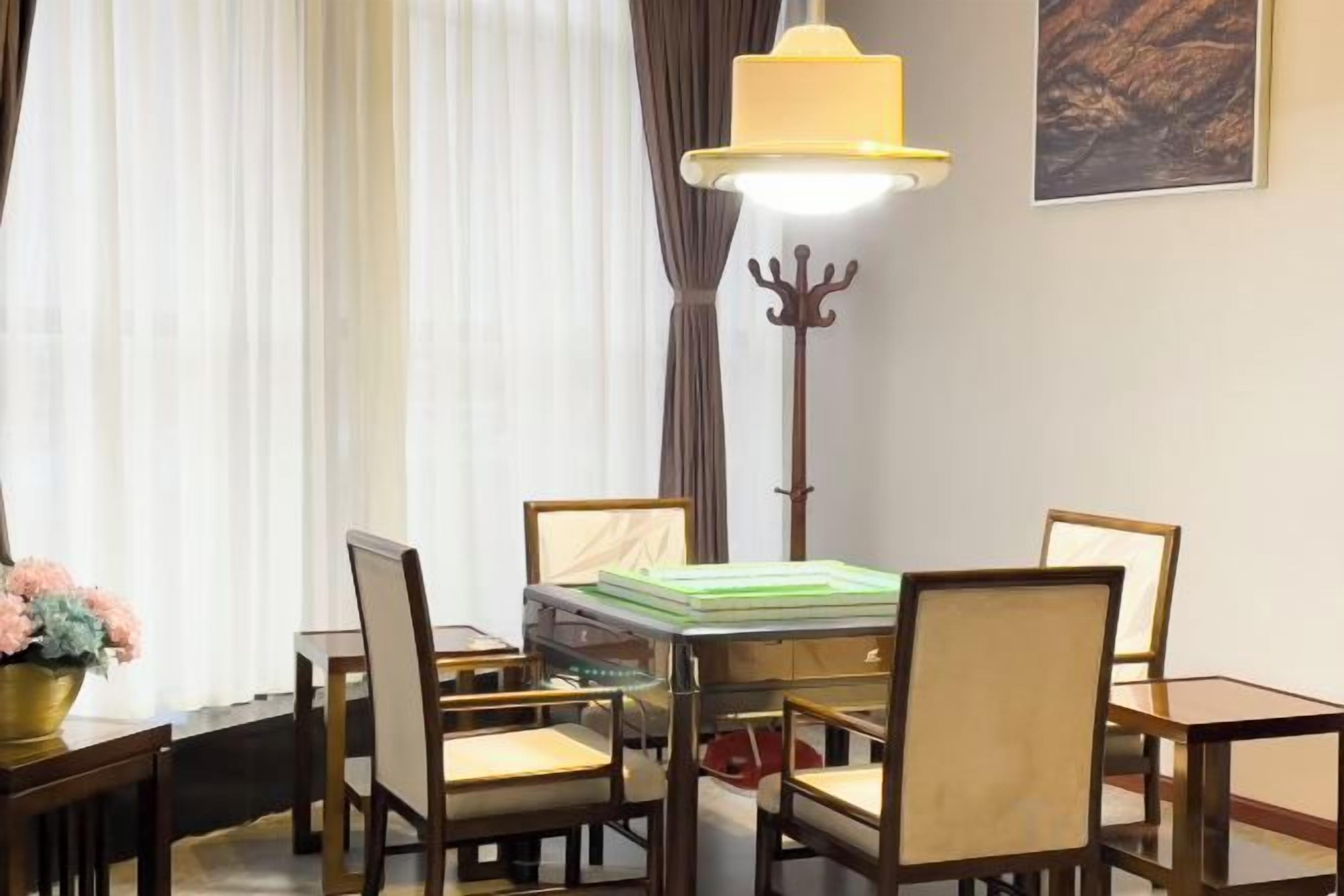 A dining area with a glass-top table surrounded by chairs, a floor lamp, and a coat rack.