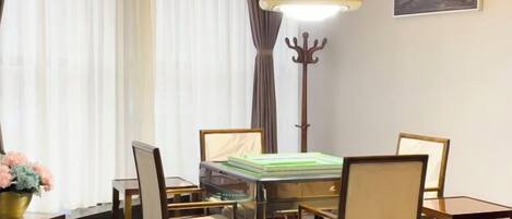 A dining area with a glass-top table surrounded by chairs, a floor lamp, and a coat rack.