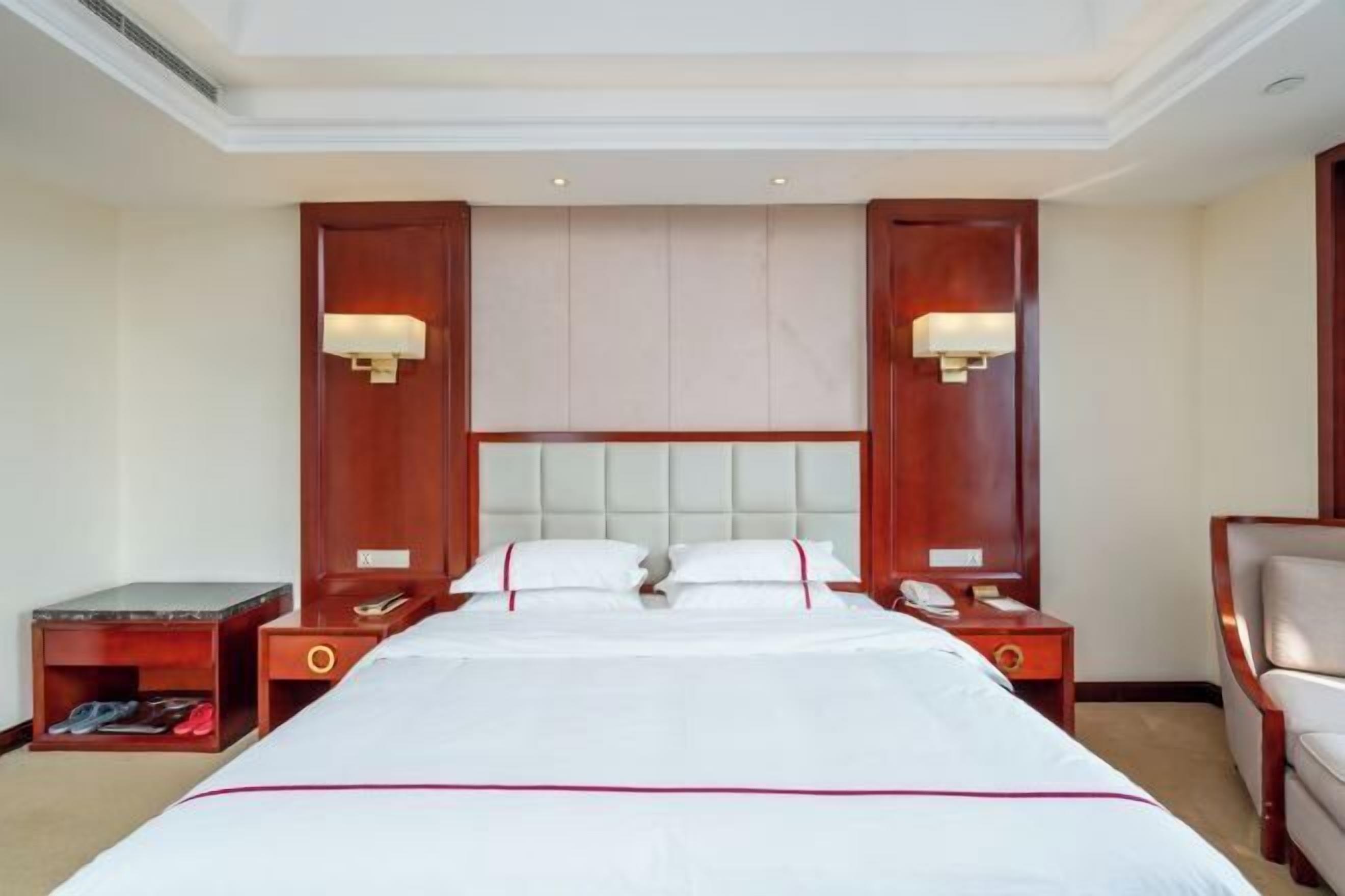 A hotel room with a large bed, two bedside tables, a nightstand, and a chair.