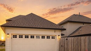 Een gelijkvloers huis met garage, houten omheining en een verzorgd gazon.