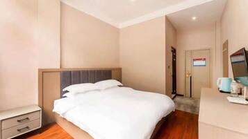 Una habitación de hotel con cama, mesita de noche y escritorio con computadora.