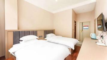 Habitación de hotel con dos camas, un escritorio de madera, un televisor y una puerta con un cartel.