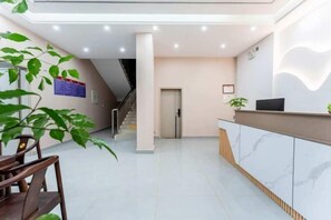 A modern reception area with a reception desk, a staircase, and a plant. - Chayu Hongsheng Hotel (Zayu)