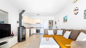 Een moderne woonkamer met een bank, een salontafel, een televisie en een keuken op de achtergrond.