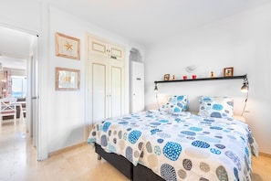 A bedroom with a bed, a wardrobe, and a shelf with decorative items.