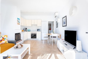 A modern apartment with a living room, kitchen, dining area, and a TV. - Calahonda Beach II | Beachfront Apartment in Calahonda (Mijas Costa)