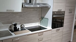 Et moderne køkken med indbygget komfur, mikroovn og emhætte i rustfrit stål.