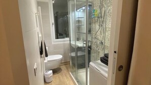Et moderne badeværelse med brusekabine i glas, toilet og håndvask.