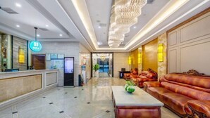 Eine geräumige Lobby mit einer Rezeption, einer Kandelaber, Ledersofas und einem Marmorboden.