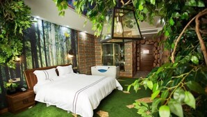 Ein Schlafzimmer mit Bett, Nachttisch, Kommode und einem Badezimmer mit Glastür.