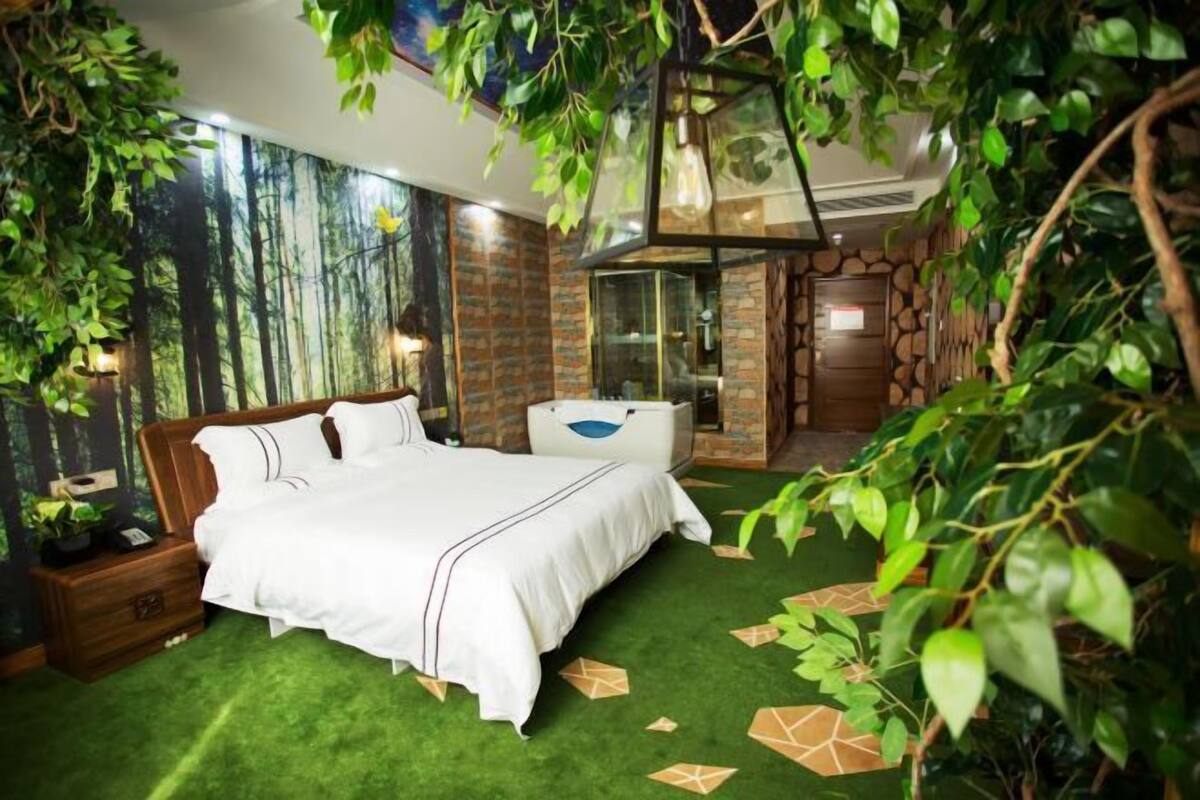 A bedroom with a bed, a nightstand, a dresser, and a bathroom with a glass door.
