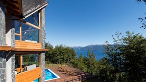 Un edificio moderno con fachada de piedra, terraza de madera y piscina.