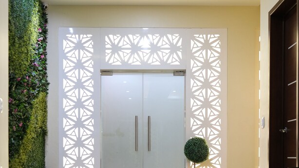 A modern interior with a reflective floor, a large white door with two handles, and a decorative wall panel. - Ivissa Hotel  (Pinotepa Nacional)