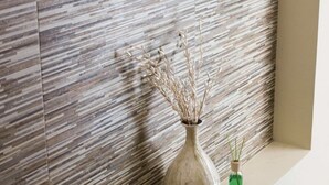 A modern interior with a textured wall and a vase with dried plants on a bench. - Ivissa Hotel  (Pinotepa Nacional)