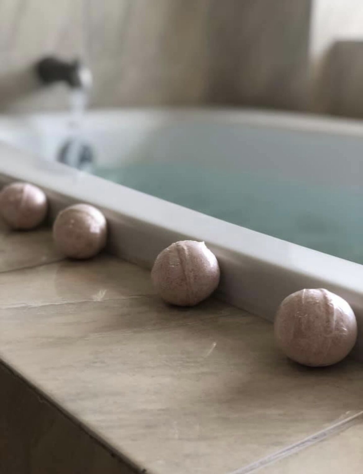 Une baignoire bordée de plusieurs tapis de bain ronds de couleur beige.