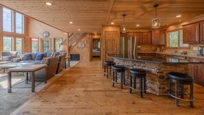 Une cuisine spacieuse avec des meubles en bois, un grand îlot central doté de tabourets et un mur d’accent en pierre.