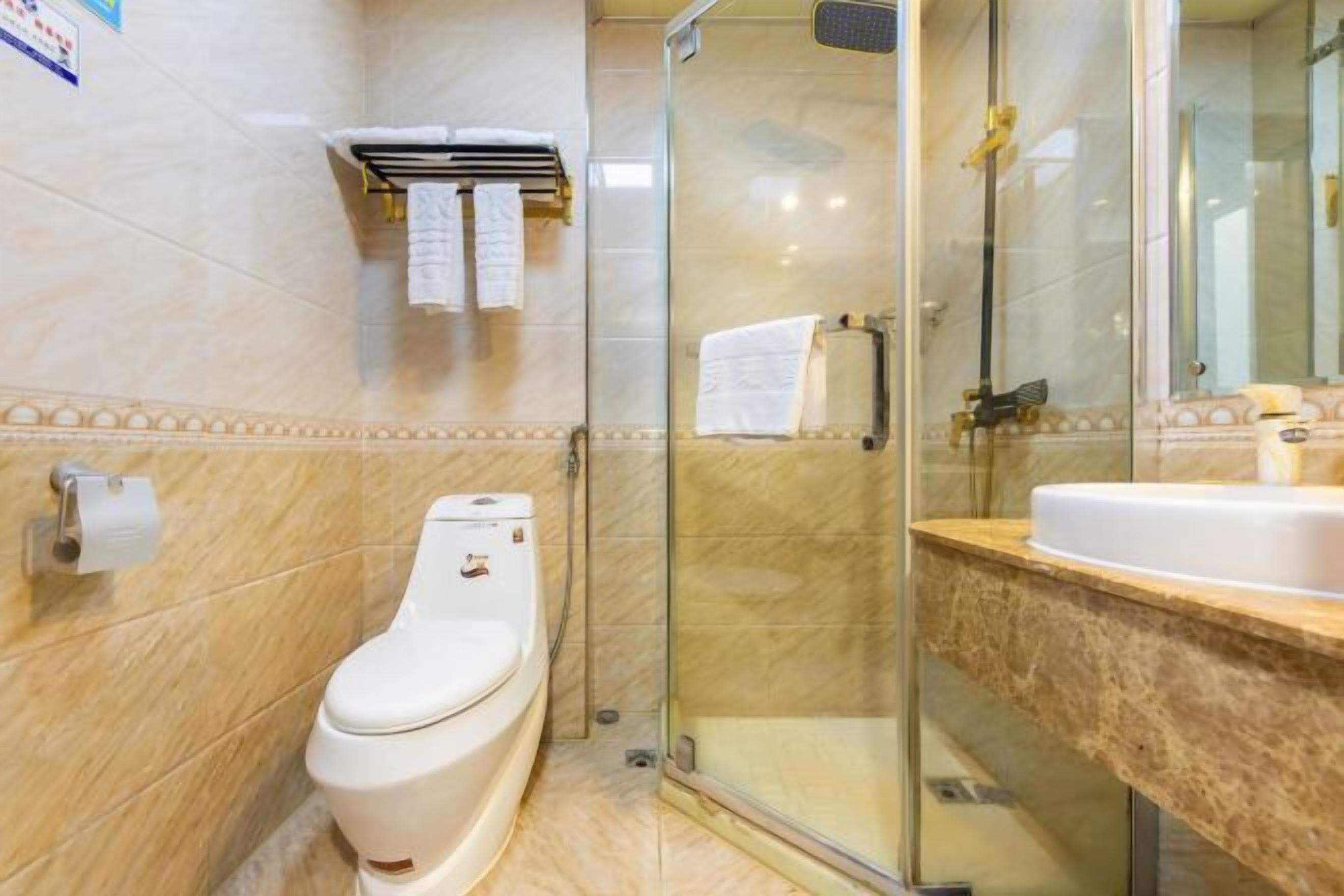 A modern bathroom with a toilet, a glass-enclosed shower, and a sink with a marble countertop.