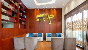 Un intérieur moderne avec des murs lambrissés en bois, une œuvre d’art représentant une carte du monde et un coin salon agrémenté de poufs gris et de canapés blancs.