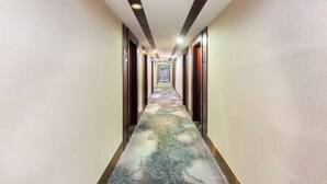 Un long couloir étroit, orné d’un tapis à motifs et doté de portes en bois de chaque côté.