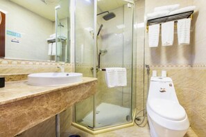 Un baño con ducha de vidrio, un lavamanos blanco y un inodoro.