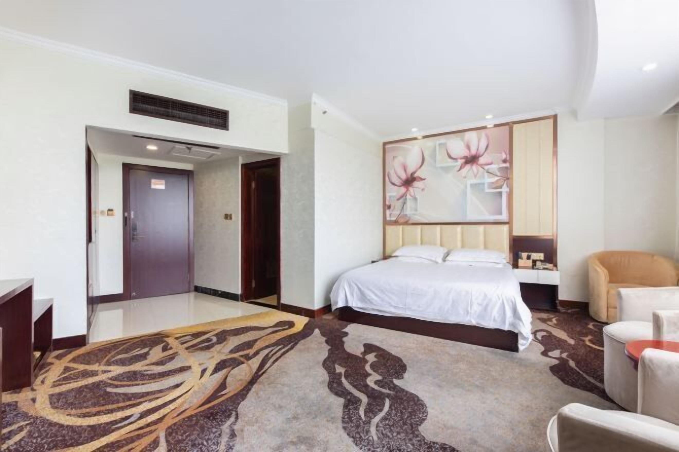 Una camera d'albergo con un letto, una sedia, una scrivania e un quadro appeso al muro.