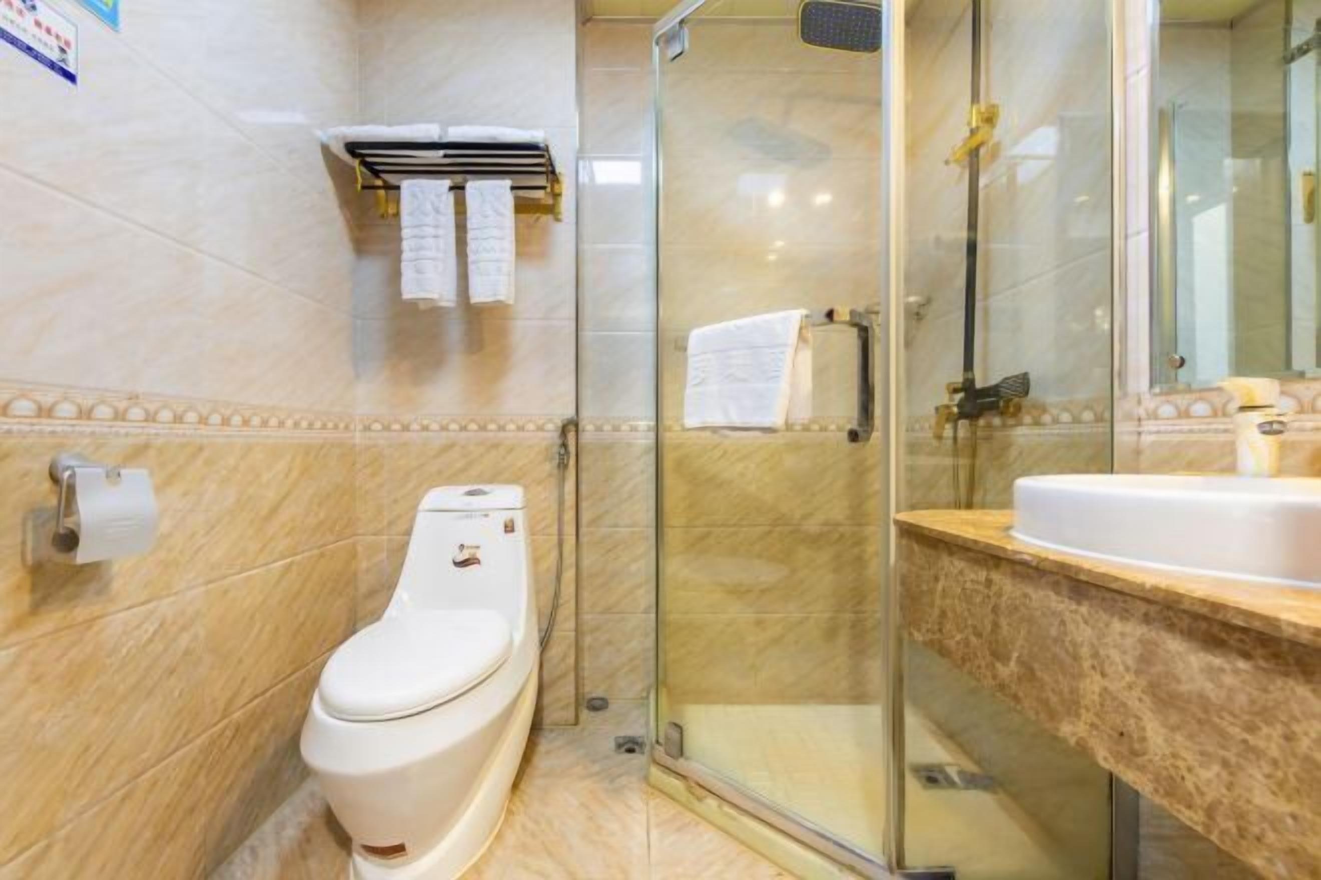 A bathroom with a toilet, a glass-enclosed shower, and a sink with a marble countertop.