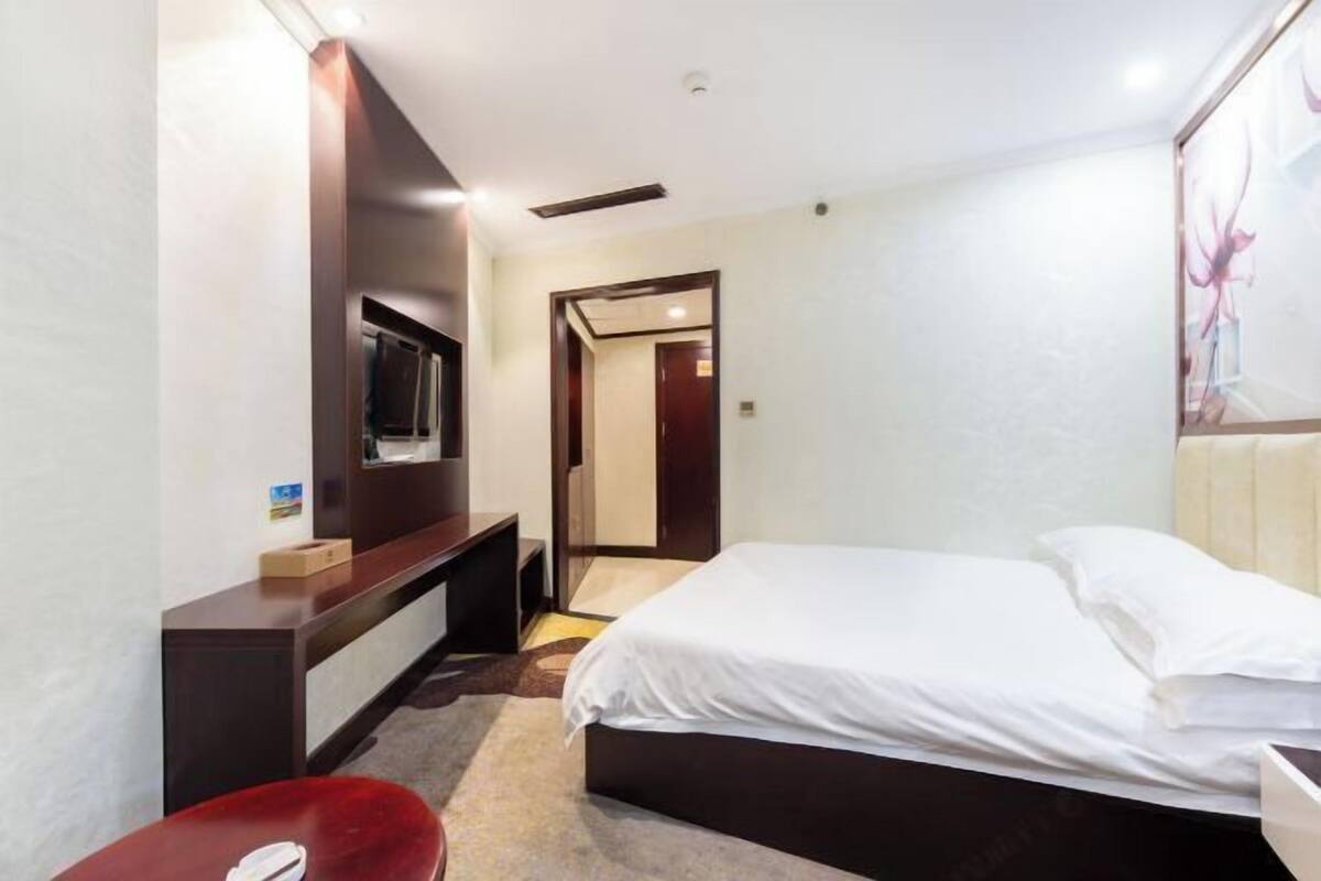 Habitación de hotel con cama, escritorio, silla, televisor y puerta que da a otra habitación.