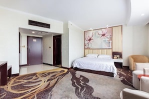 Habitación de hotel con cama, escritorio, silla y un adorno en la pared.