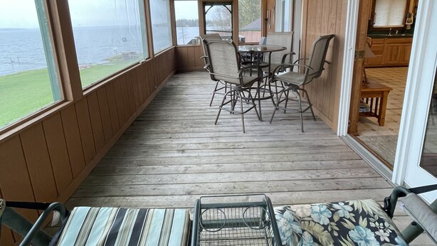A covered deck with a table and chairs, a sofa, and a view of the water.