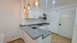A modern kitchen with white cabinets, granite countertops, and pendant lighting. - Premiere apartment near the financial center of San Isidro (Lince)