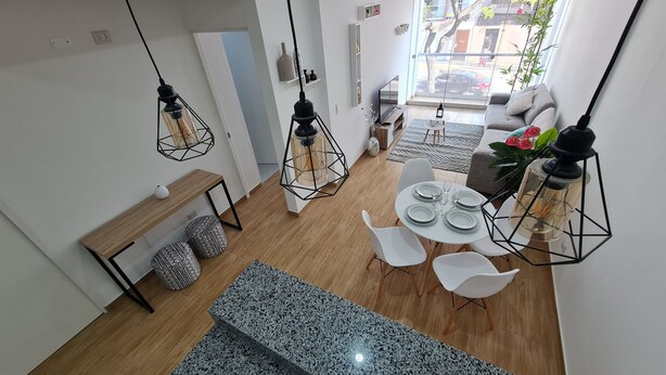 A modern living space with a dining area, a sofa, and hanging pendant lights. - Premiere apartment near the financial center of San Isidro (Lince)