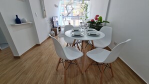 A dining area with a round table, white chairs, and a vase of flowers. - Premiere apartment near the financial center of San Isidro (Lince)