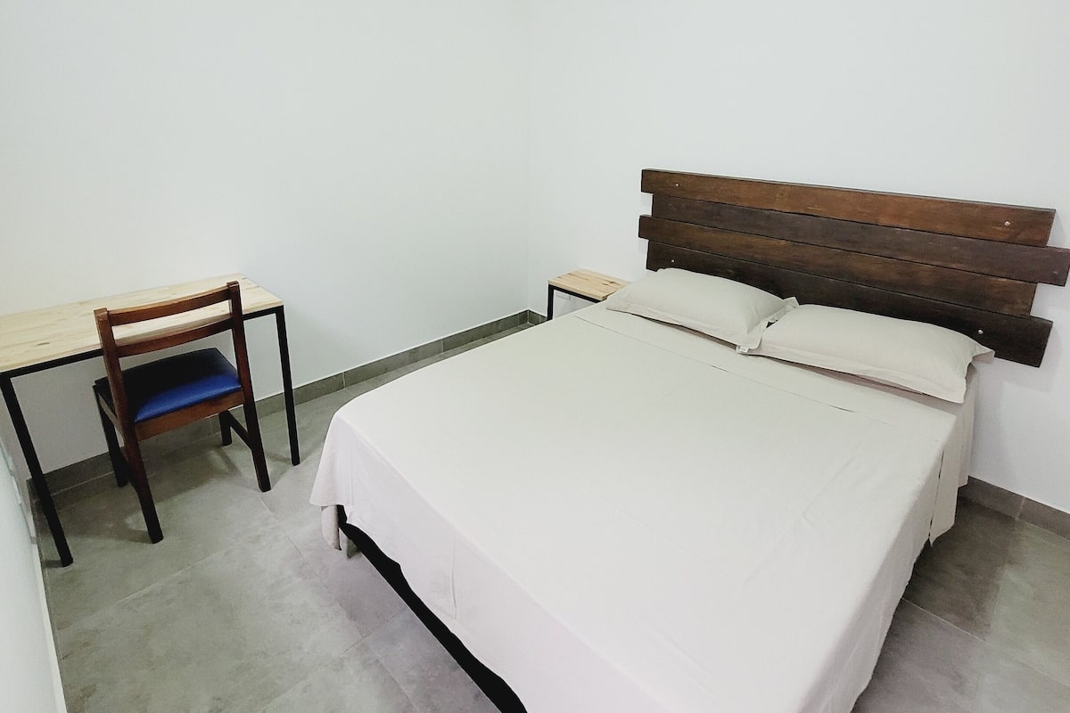 A room with a bed, a desk, and a chair.