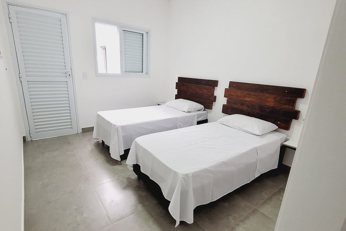A room with two beds, a window, and a door.