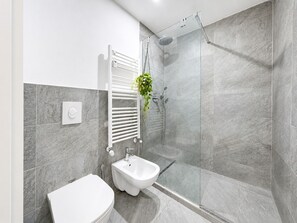 A modern bathroom with a glass shower enclosure, a bidet, and a towel rack. - Stagabin - Lofts within walking distance of subway and Porta Susa (Torino)