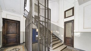 A staircase with a metal railing, a wooden door, and a tiled floor with a geometric pattern.