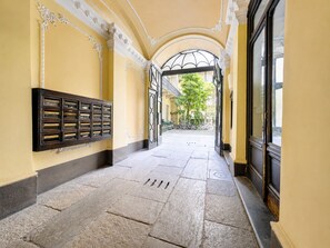 Un couloir doté d’un sol en pierre, d’une grille métallique et d’une vitrine fixée au mur.