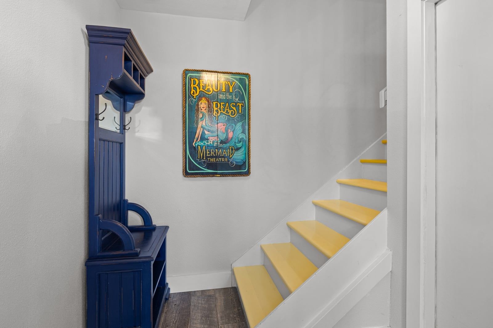 A staircase with yellow steps leading to a landing where a framed poster is displayed.