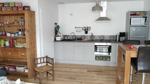 A modern kitchen with white cabinets, a wooden chair, and a dining table.