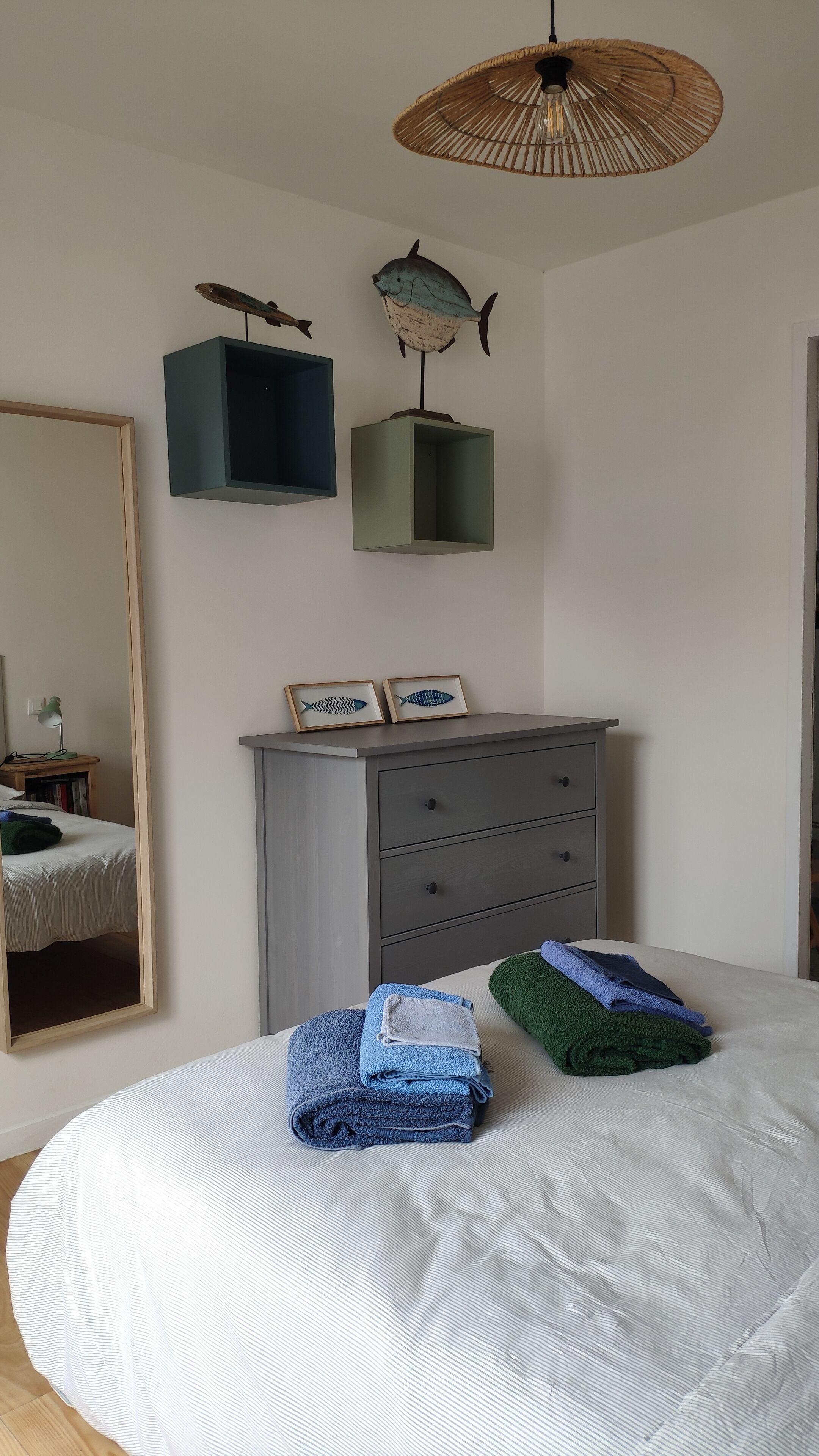 A bedroom with a bed, a dresser, a mirror, and wall-mounted fish decorations.