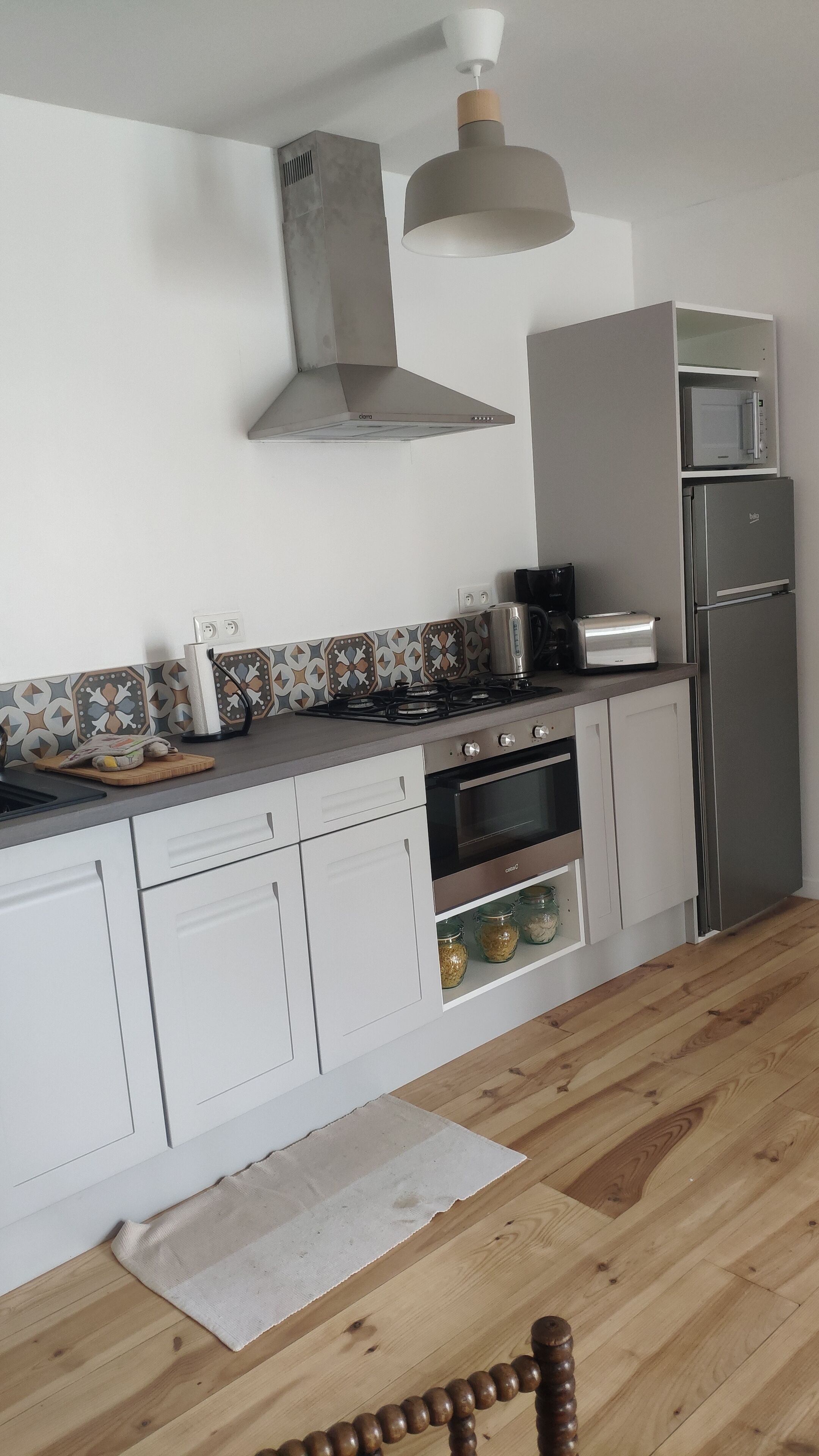 A modern kitchen with a gas stove, oven, microwave, and a stainless steel refrigerator.