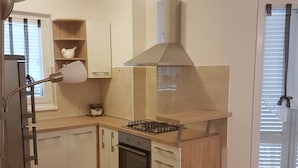 Una cocina moderna con armarios blancos, estufa a gas, horno integrado y campana extractora de acero inoxidable.